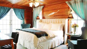 A bedroom with a large bed, a wooden ceiling, and a window with curtains.