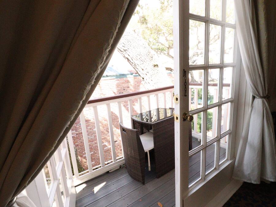Una habitación con un ventanal grande, una silla de mimbre y una mesita.