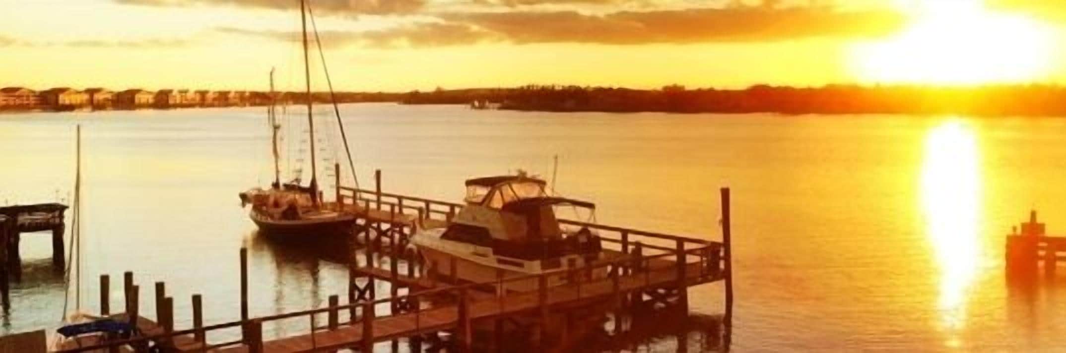 Une jetée où sont amarrés des bateaux, au coucher du soleil.