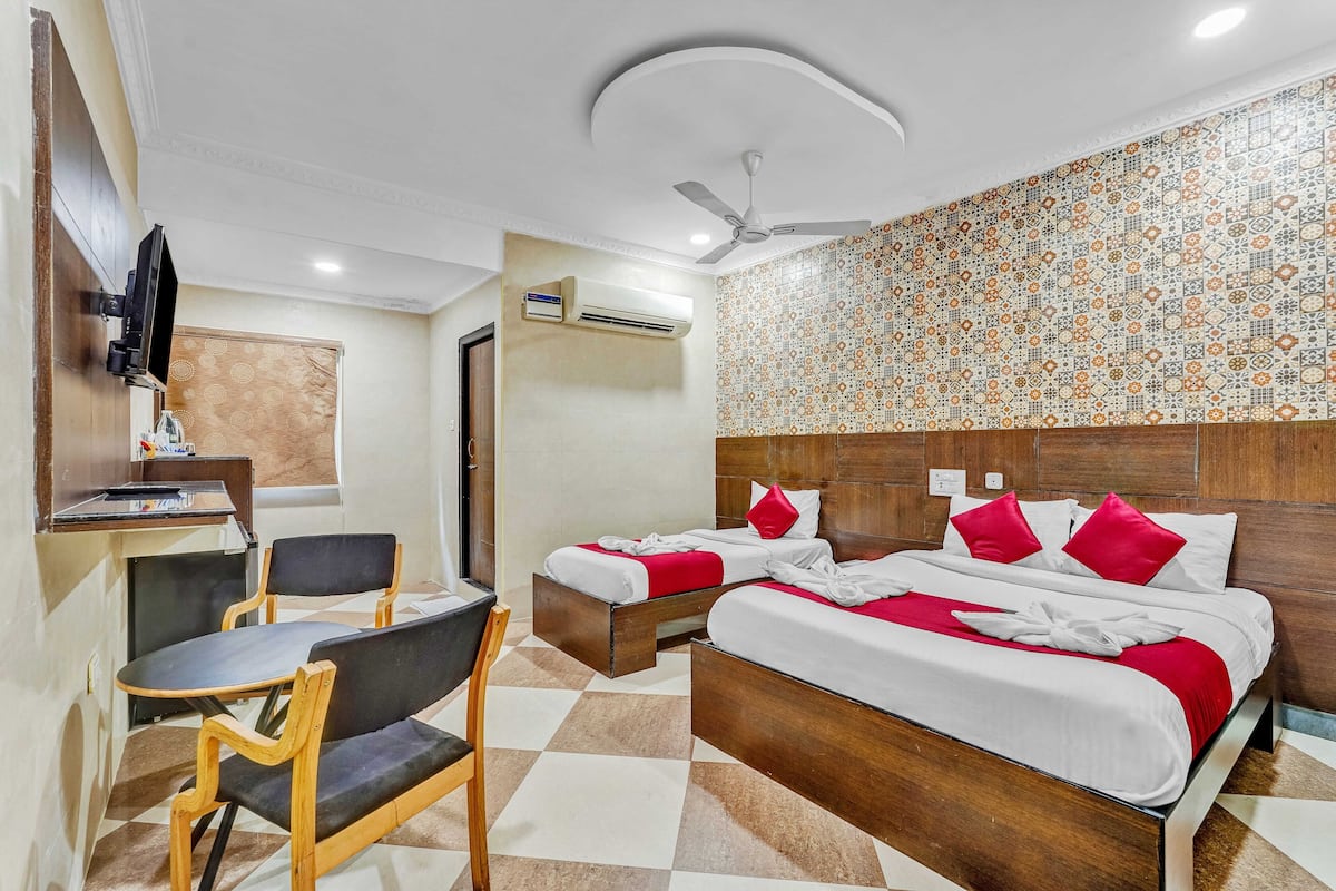 Ein Hotelzimmer mit zwei Betten, einem Schreibtisch, Stühlen, einem Fernseher und einer Klimaanlage.