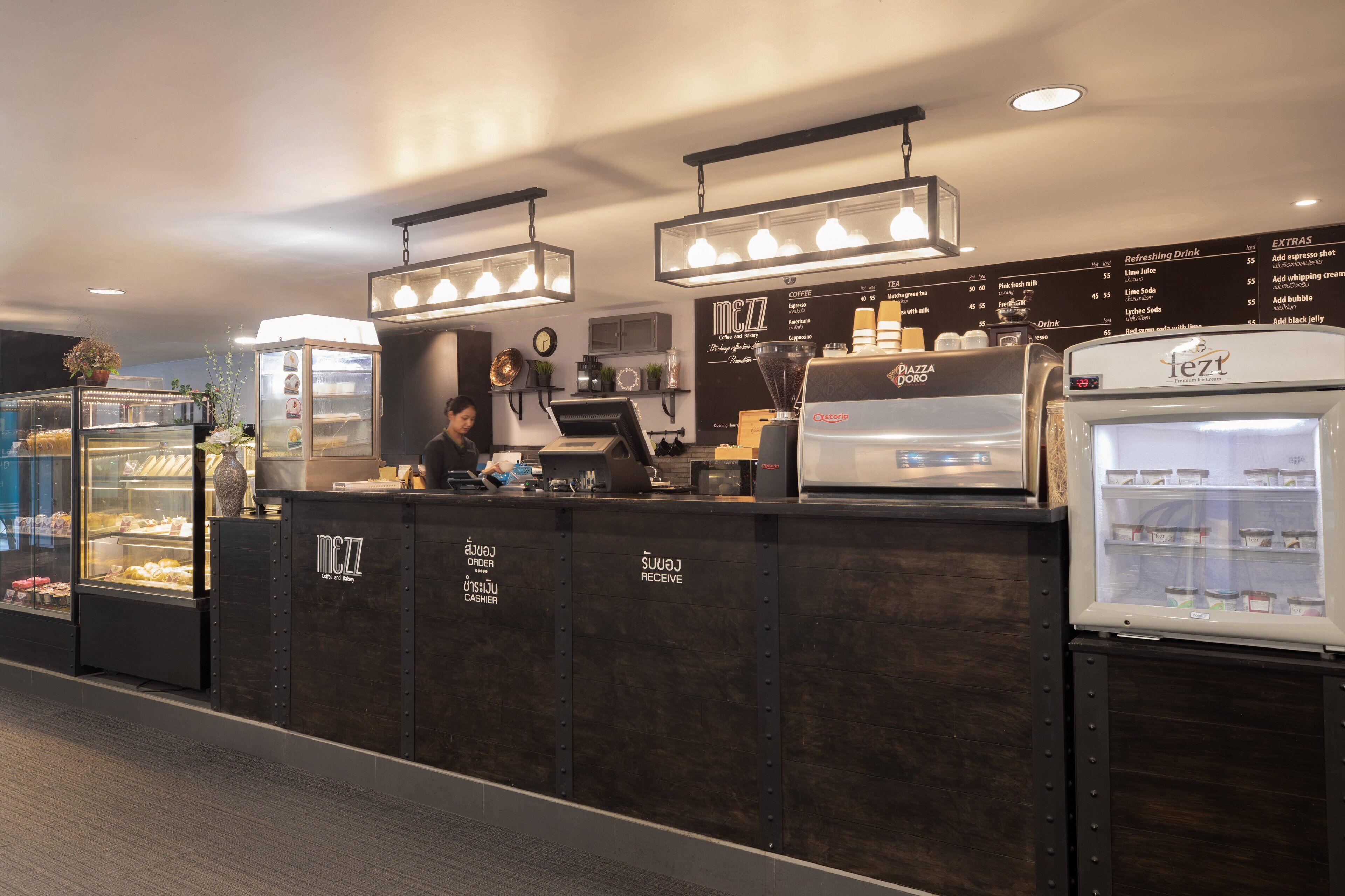 A coffee shop interior with a counter, a refrigerated display case, and a menu board.