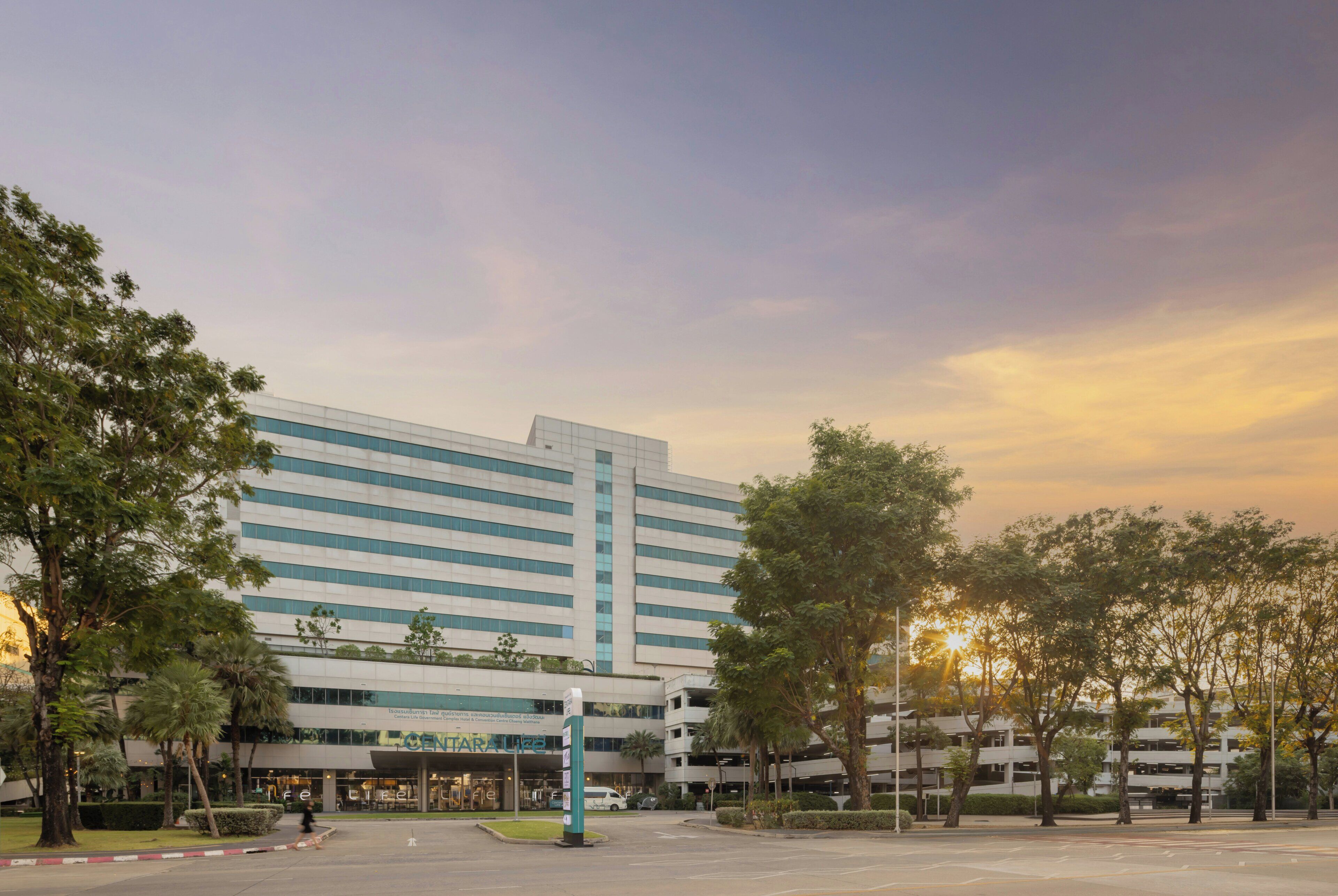 A modern building with a flat roof, large windows, and a parking structure.