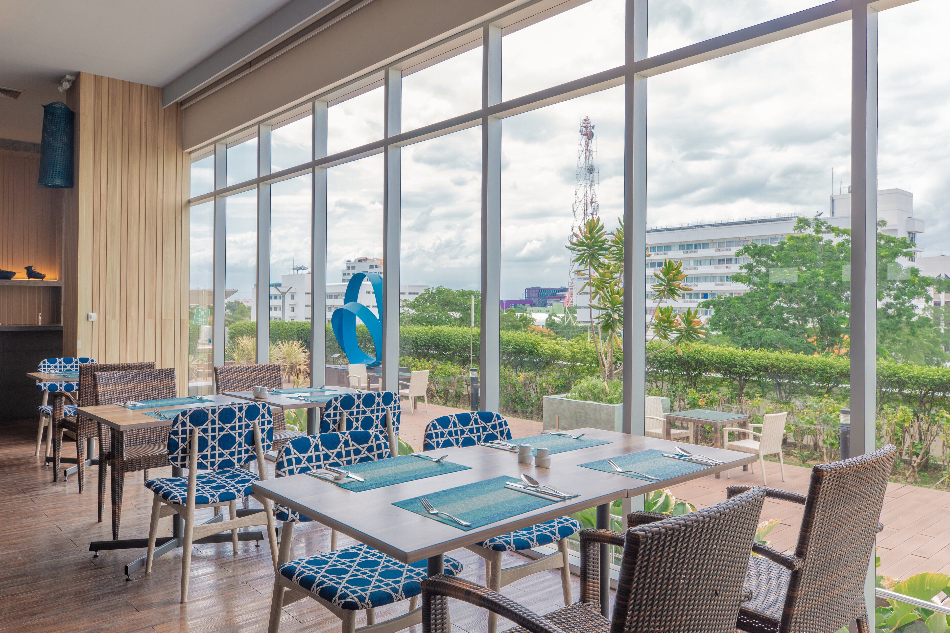 A restaurant with large windows, wicker furniture, and a view of the city.