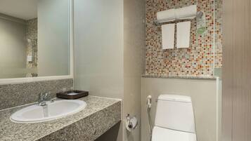 Un baño con lavamanos de encimera de granito, inodoro y ducha.