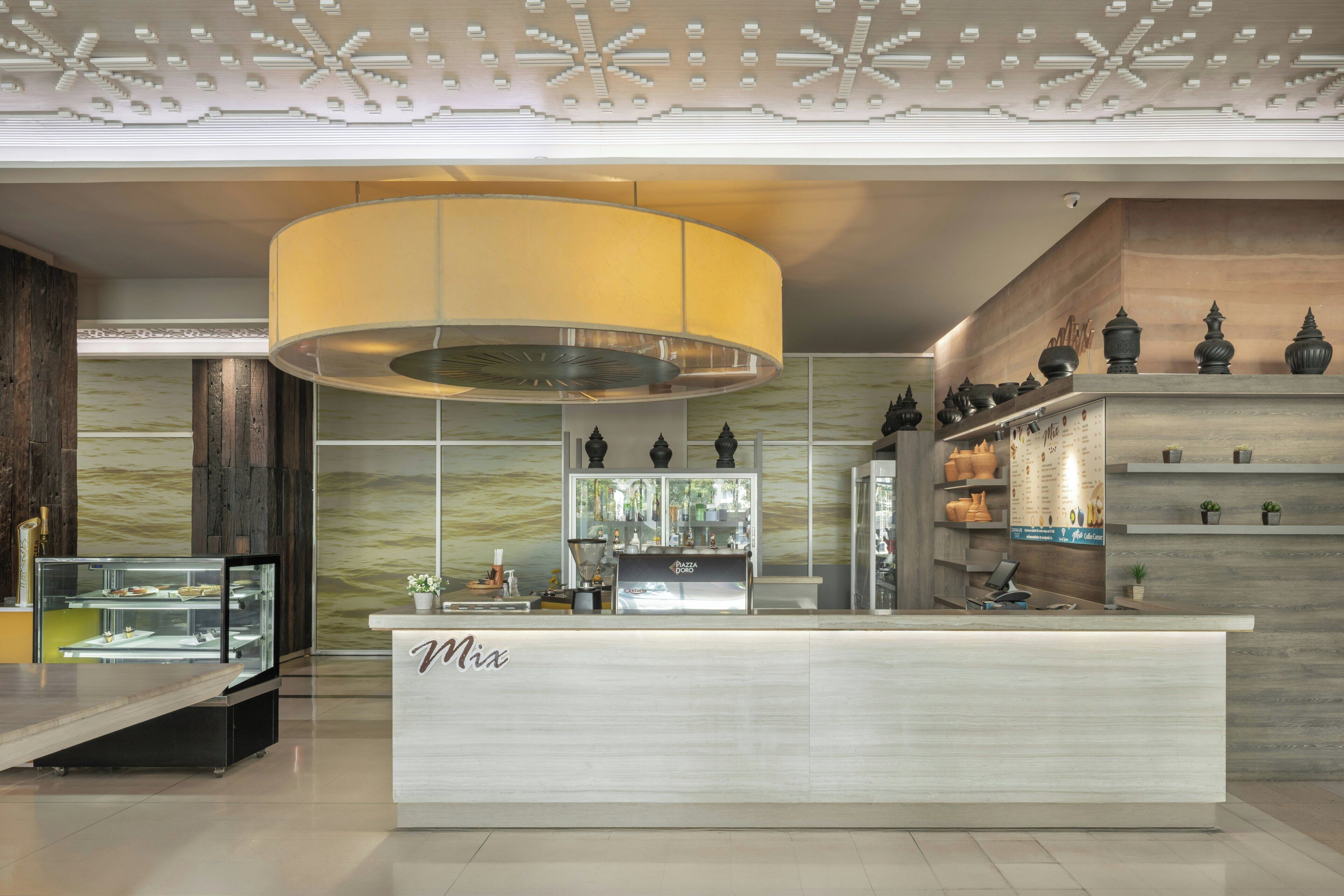 A modern reception desk with a 'Mix' sign, a glass display case, a large overhead lamp, and decorative vases on shelves.