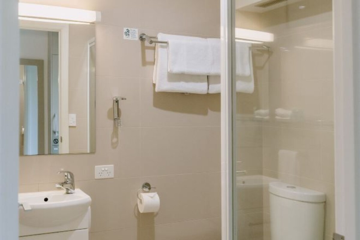 A bathroom with a sink, toilet, and glass shower enclosure.