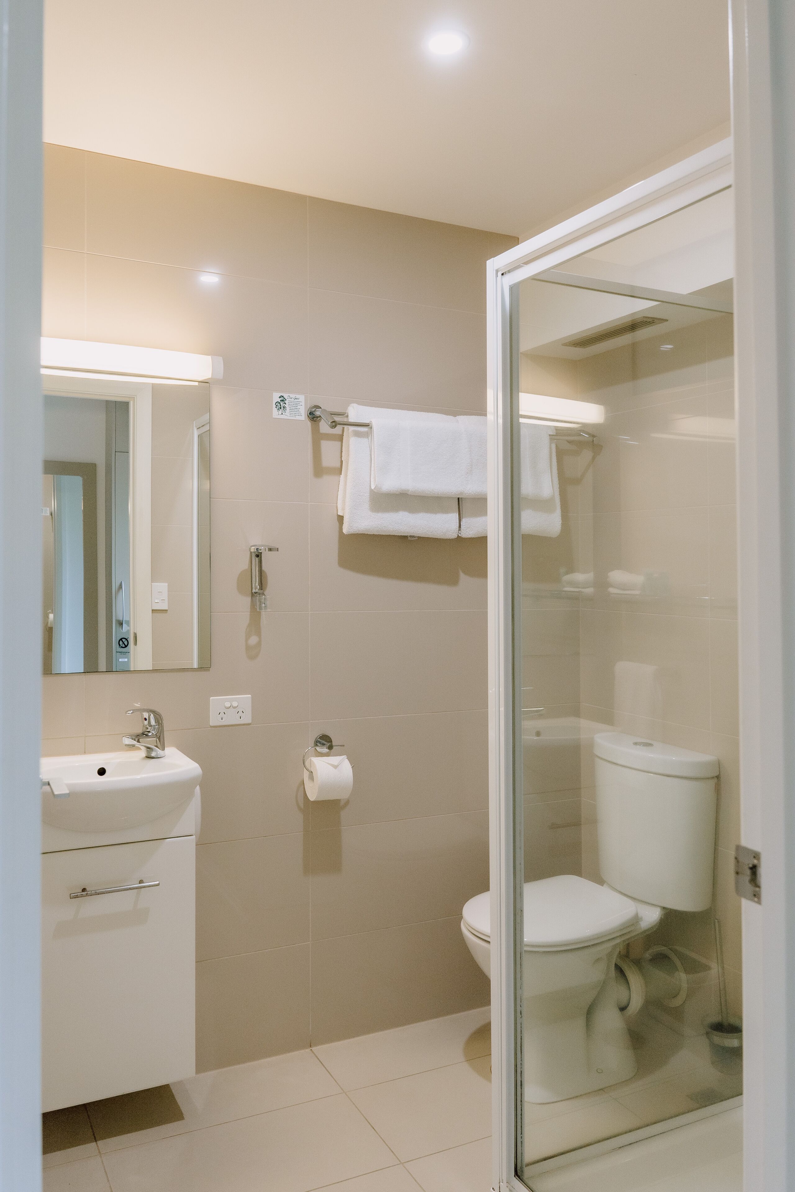 A modern bathroom with a glass-enclosed shower, a white sink, and a toilet.