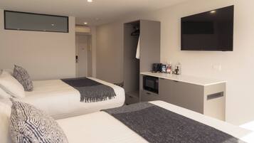 A modern hotel room with two beds, a flat-screen TV, a microwave, and a small kitchenette.