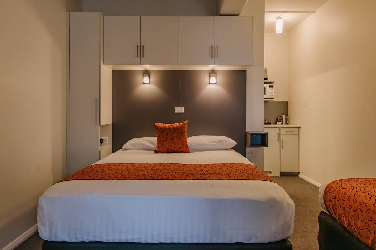 Quarto de hotel com cama, escrivaninha e guarda-roupa.