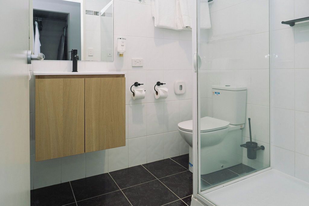 A modern bathroom with a toilet, bidet, and a glass shower enclosure.