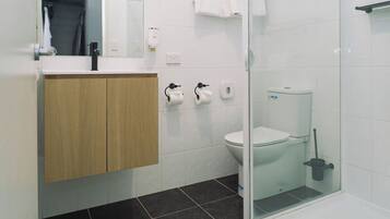 A modern bathroom with a toilet, bidet, and a glass shower enclosure.