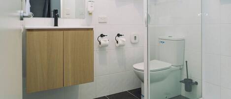 Un baño moderno con inodoro, bidé y cabina de ducha de vidrio.