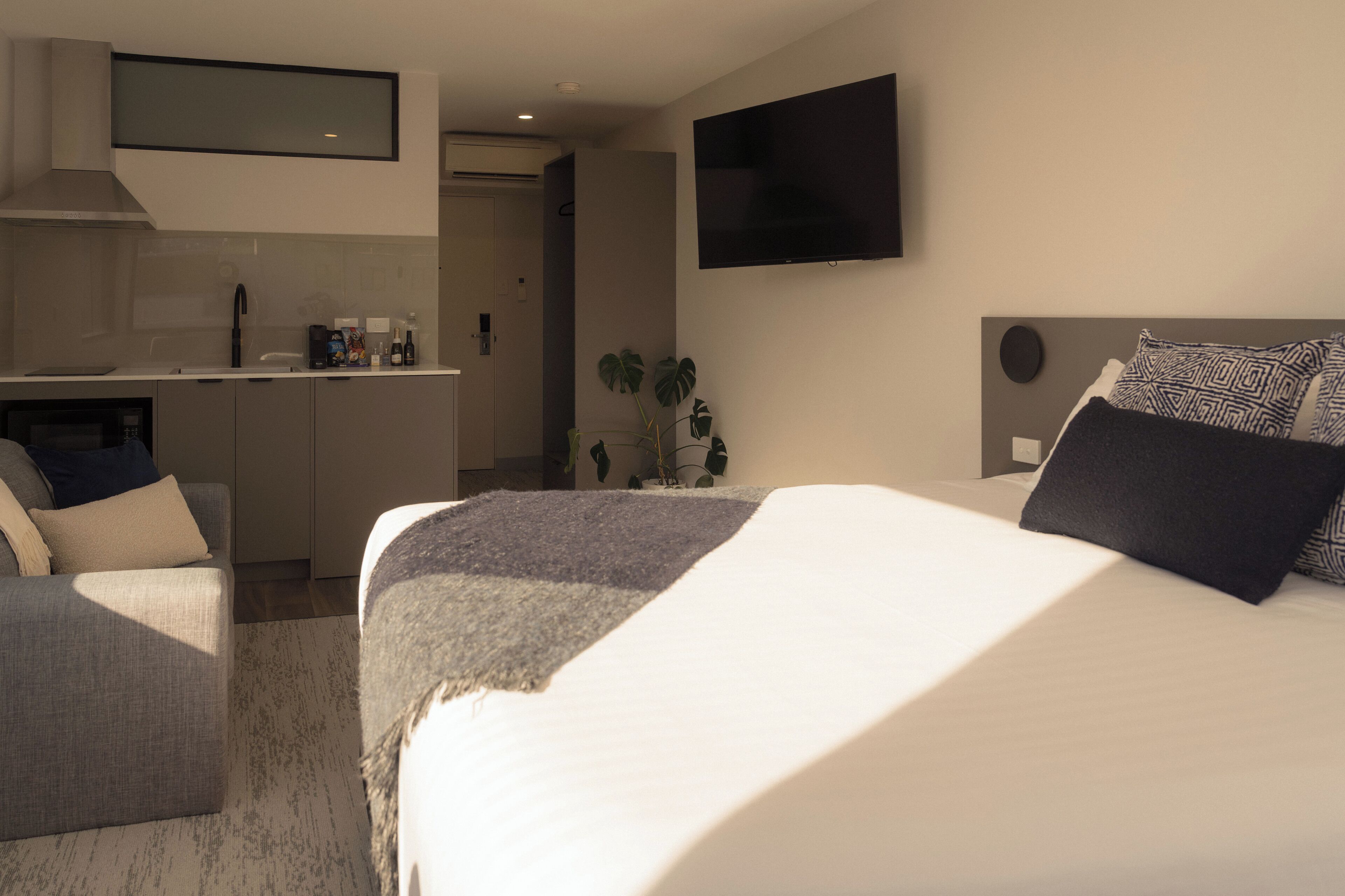 Ein modernes Hotelzimmer mit einem großen Bett, einem Schreibtisch und einem Flachbildfernseher.