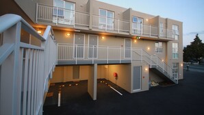 Ein mehrgeschossiges Hotel mit Balkonen, einer Treppe und einem Parkplatz.