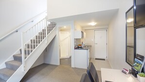 Eine moderne Wohnung mit Treppe, einer kleinen Küche und einem Essbereich.