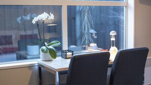 Ein Essbereich mit Tisch, Stühlen, einer Topforchidee und einer Lampe.