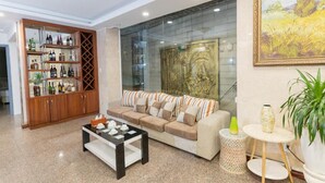 A living room with a sofa, coffee table, and a glass partition with artwork. - A25 Hotel - 14 Luong Huu Khanh (Ho Chi Minh City)