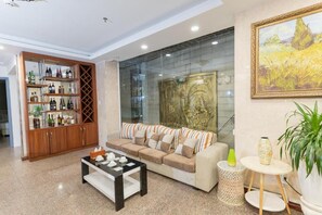 Un salon comprenant un canapé, une table basse et une cloison en verre ornée d’œuvres d’art.