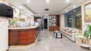 A hotel lobby with a reception desk, bar area, seating, and a display of various amenities.