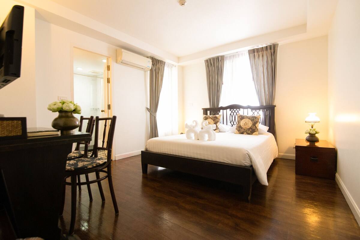 Une chambre à coucher comprenant un lit, un bureau, une chaise et une table de chevet avec une lampe.