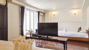 Une chambre d’hôtel avec un grand lit, une télévision, un bureau et un deuxième lit.