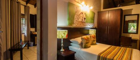 A bedroom with a bed, nightstands, a mirror, a painting, and a wardrobe.