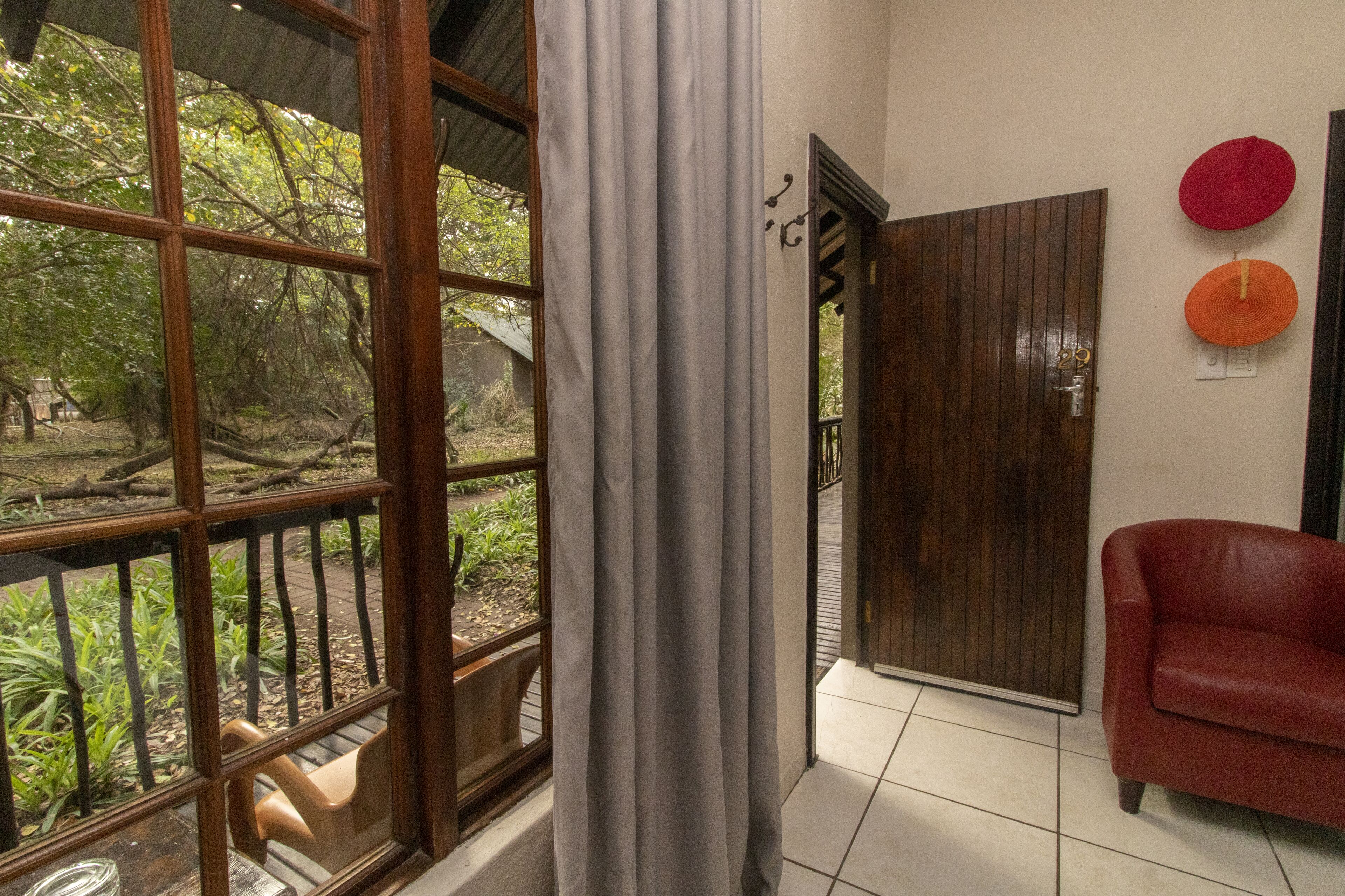 A room with a large window, a wooden door, and a red sofa.