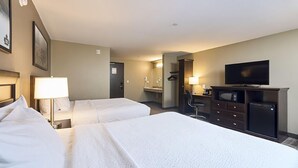 A hotel room with two beds, a television, a desk with a chair, and a mirror.