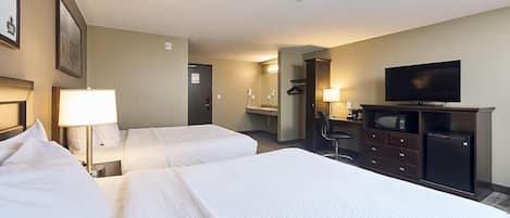 Una habitación de hotel con dos camas, televisión, escritorio con silla y espejo.