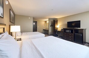 A hotel room with two beds, a television, a desk with a chair, and a mirror.