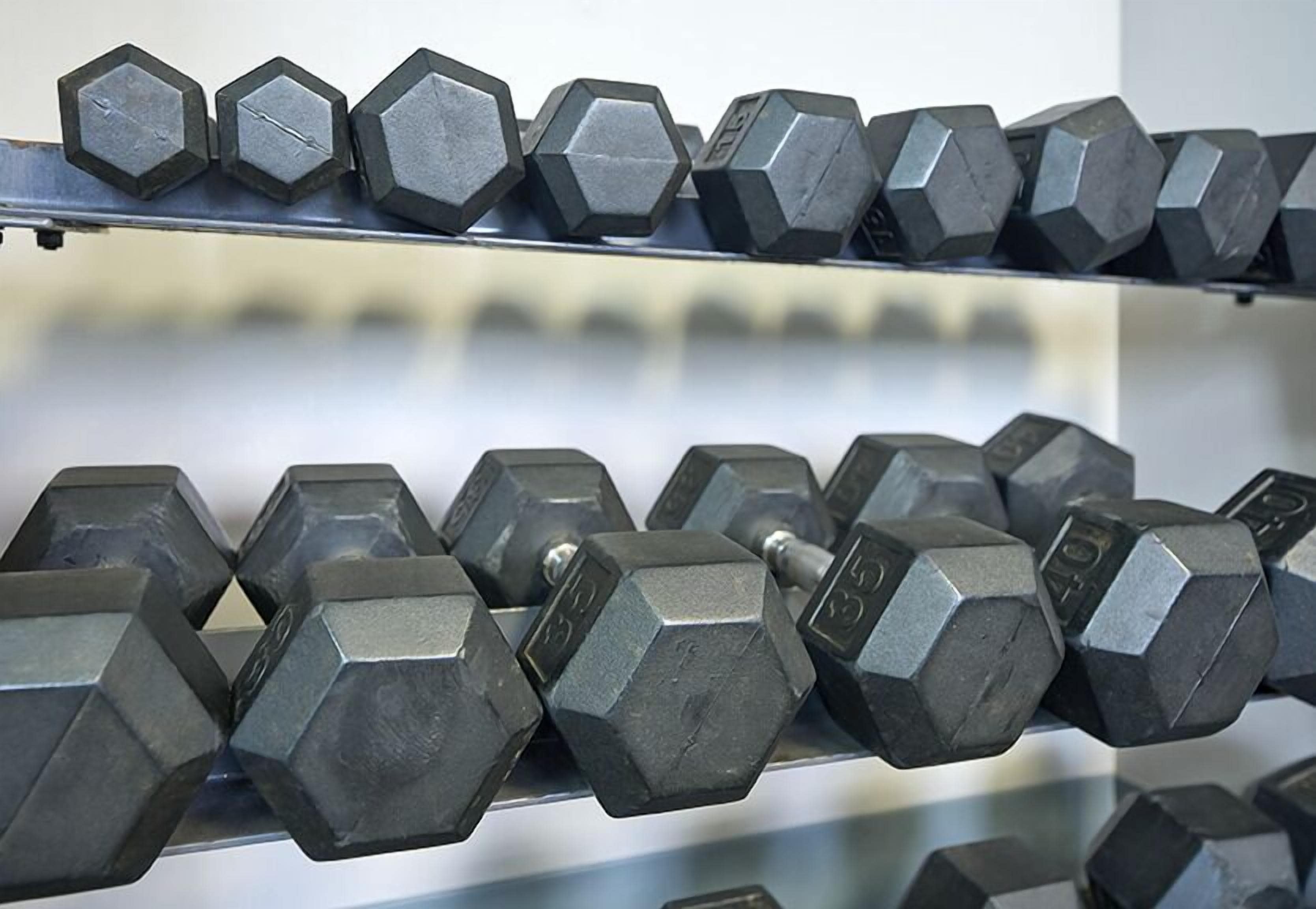 A rack of hexagonal dumbbells with visible weight markings.