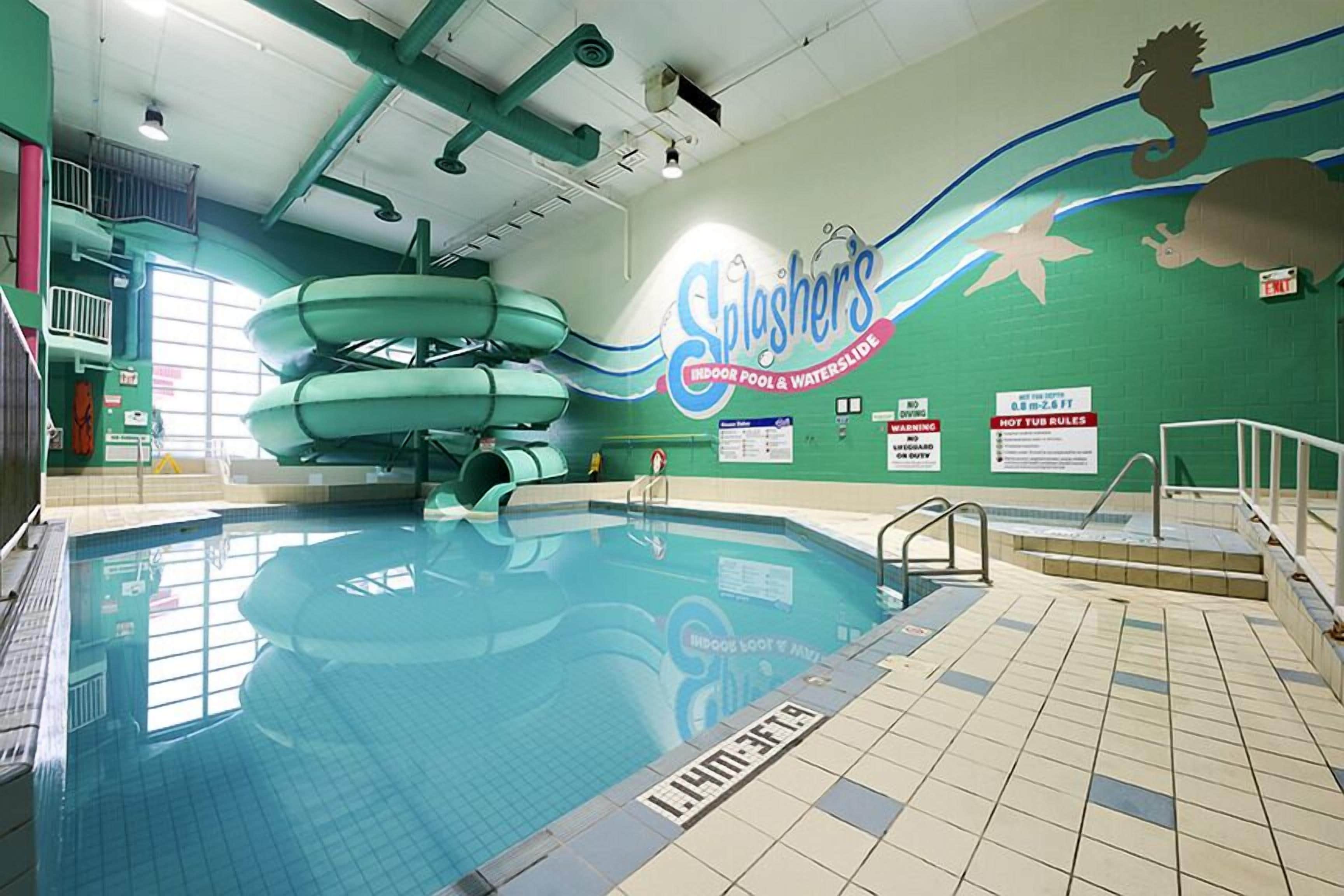 Une piscine intérieure avec des toboggans et un panneau indiquant : « Splashers, piscine intérieure et toboggan aquatique ».