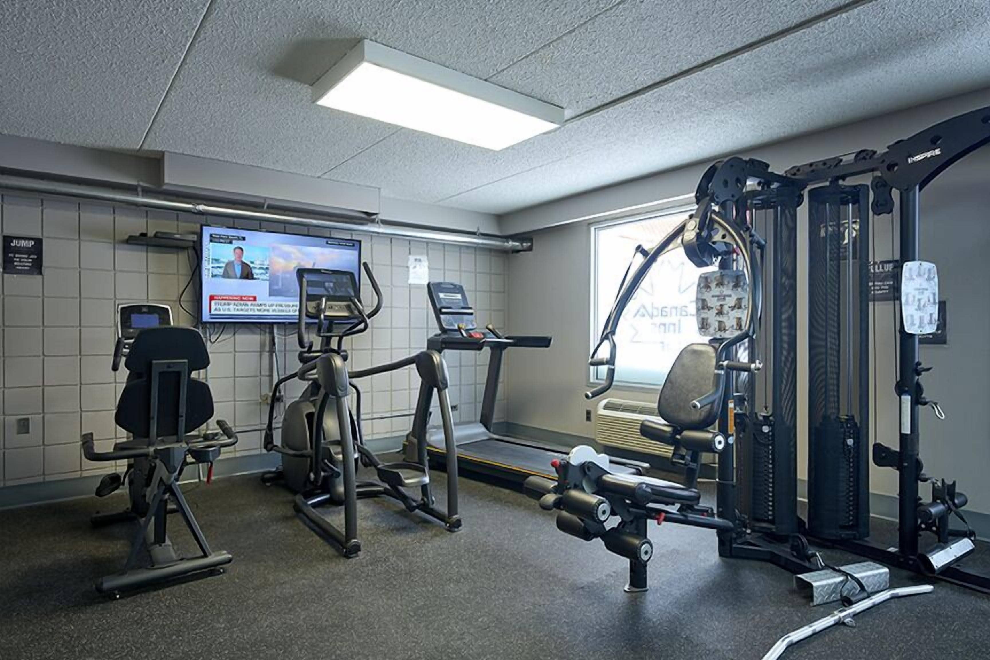 Une salle de sport équipée de machines de cardio, de matériel de musculation et d’un écran de télévision diffusant un programme d’information.