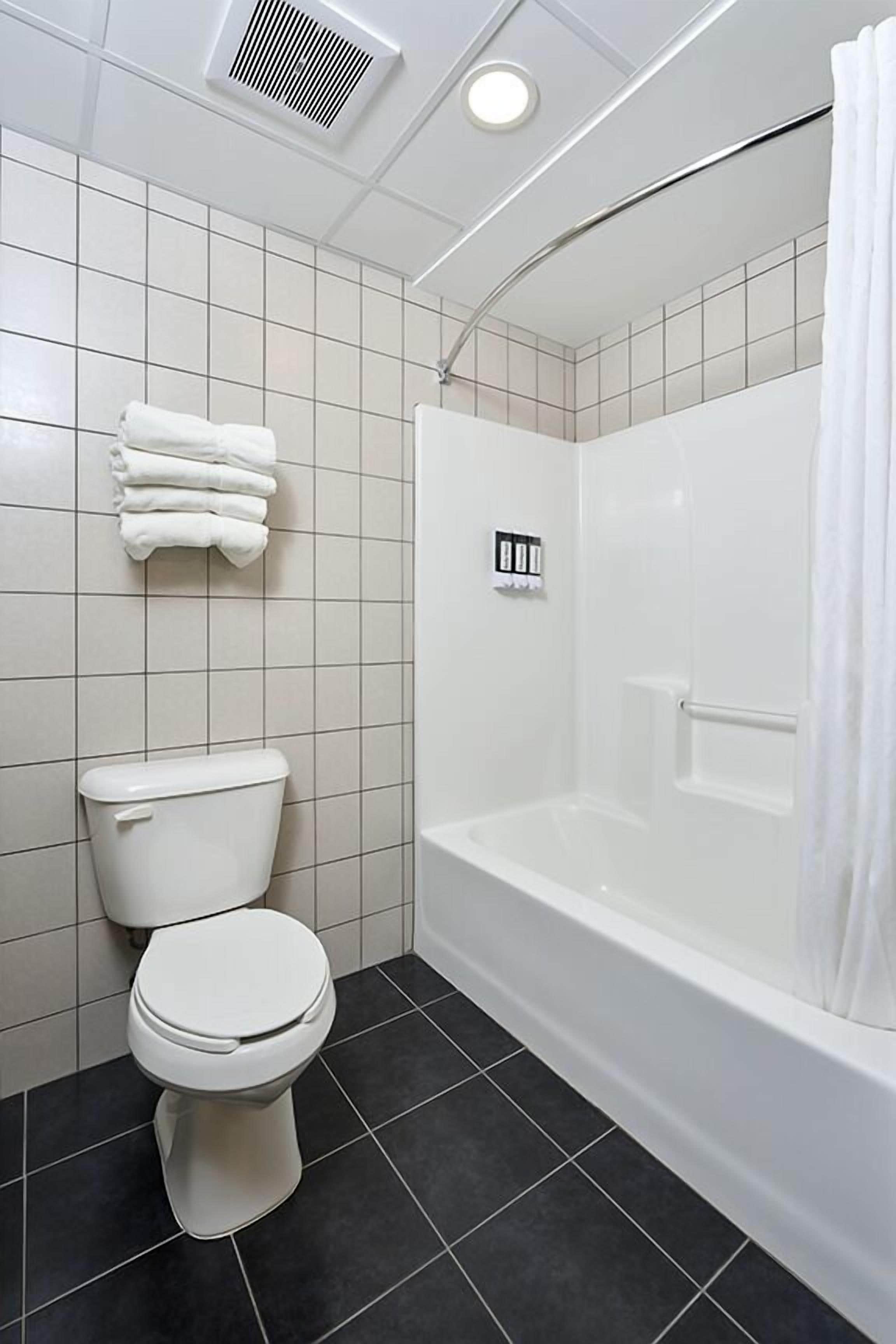 Een moderne badkamer met toilet, bad en douche.