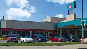 A Canada Bus building with a red and white sign, a parking lot with several cars, and a clear blue sky.
