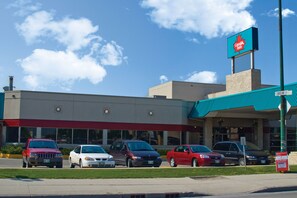 A Canada Bus building with a red and white sign, a parking lot with several cars, and a clear blue sky.