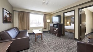 Une chambre d’hôtel avec un canapé, une télévision, un bureau, une lampe et un lit.