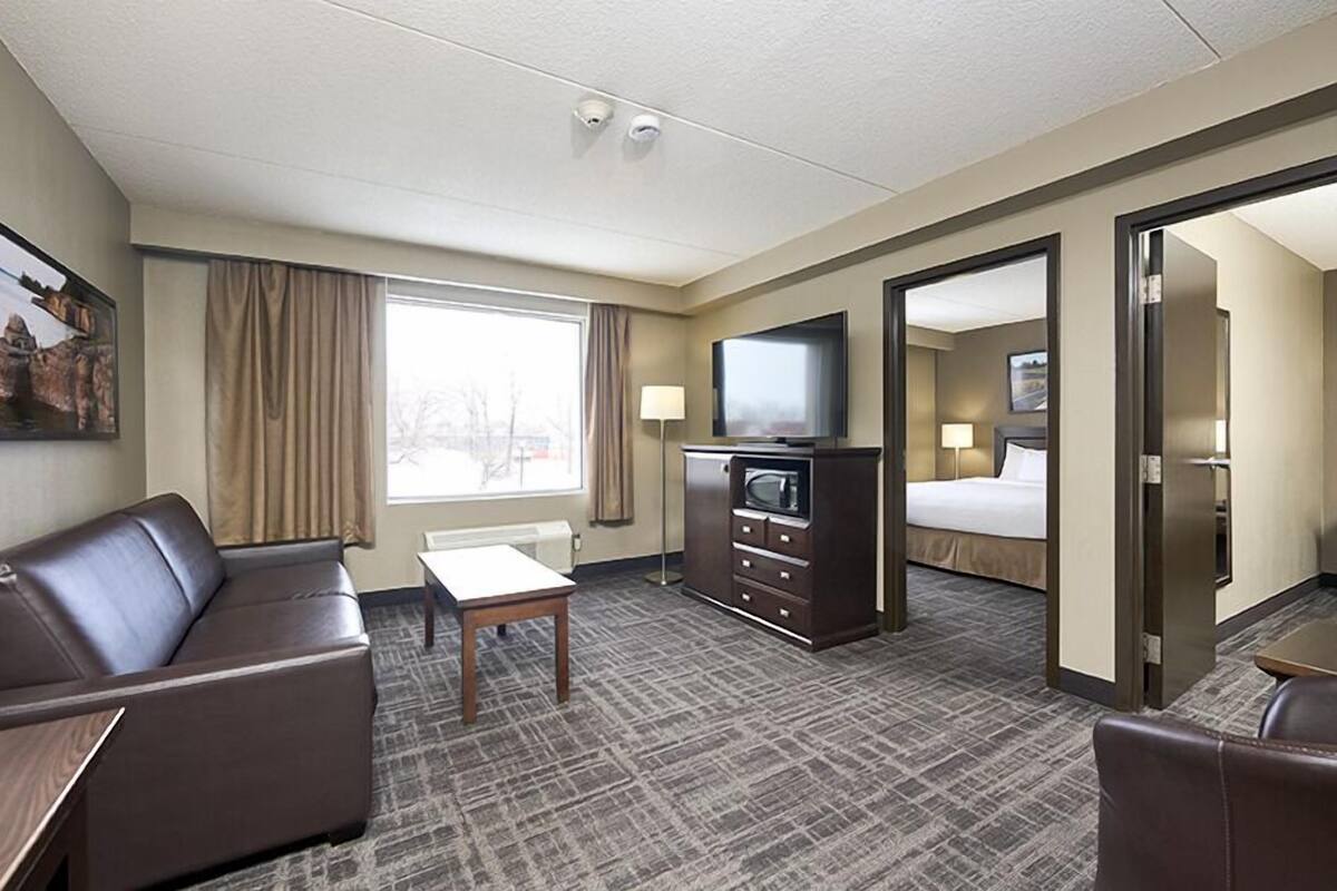 Una habitación de hotel con sofá, televisión, escritorio, lámpara y cama.