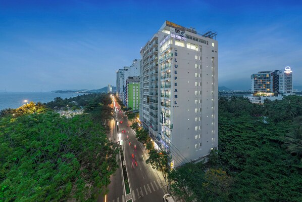 A high-rise hotel with multiple floors, balconies, and a view of the sea.