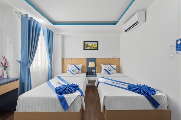 A hotel room with two beds, a desk, a nightstand, a lamp, and a painting on the wall. - Blue Pearl Hotel (Nha Trang)