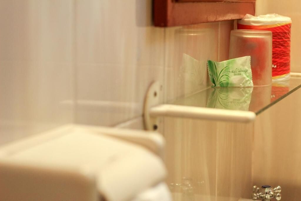 A bathroom with a glass shower enclosure, a soap dispenser, and a candle on the counter.