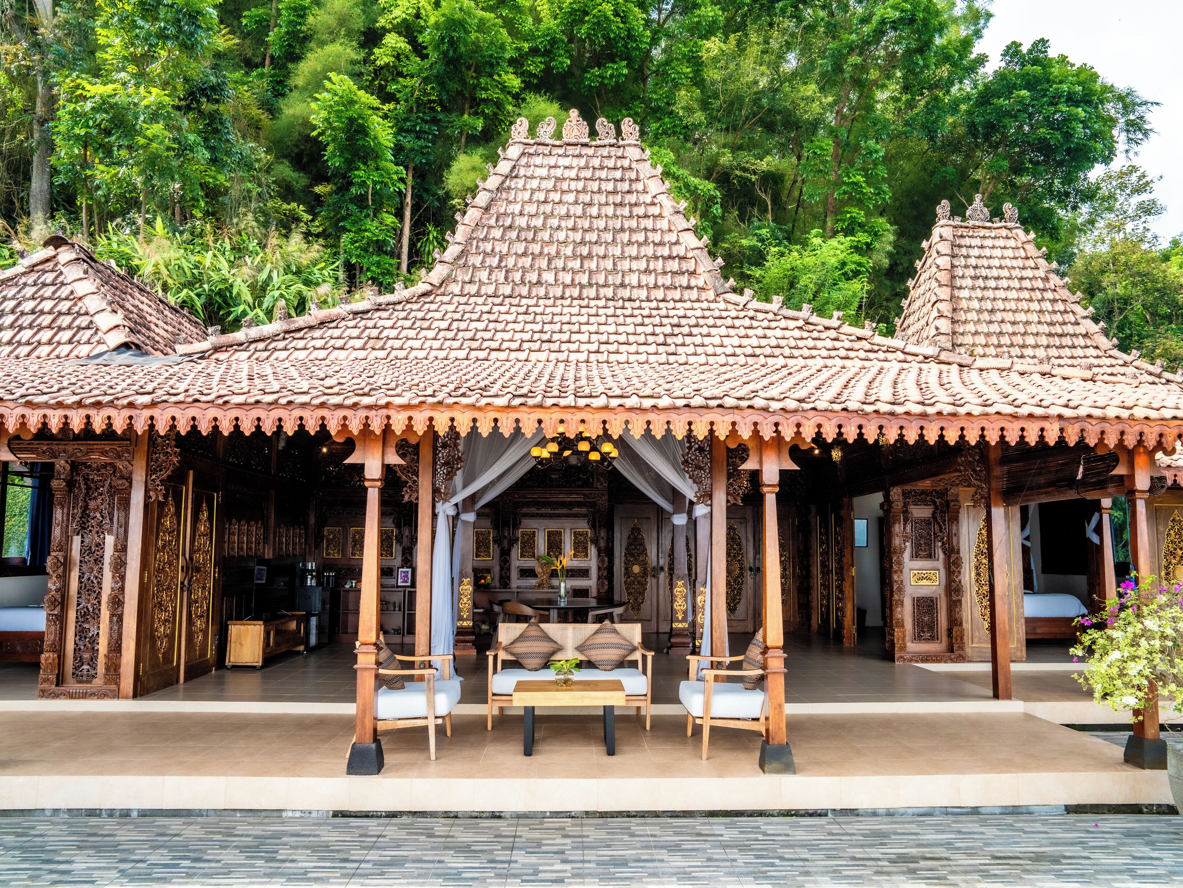 Ein traditioneller hölzerner Pavillon mit einem Ziegeldach, umgeben von üppigem Grün.
