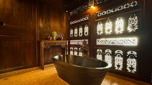 Una bañera en una habitación con paredes estampadas y suelo de madera.