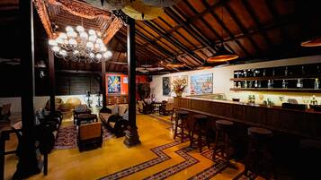 A bar area with a wooden ceiling, a bar counter with bottles, and a seating area with a patterned floor.