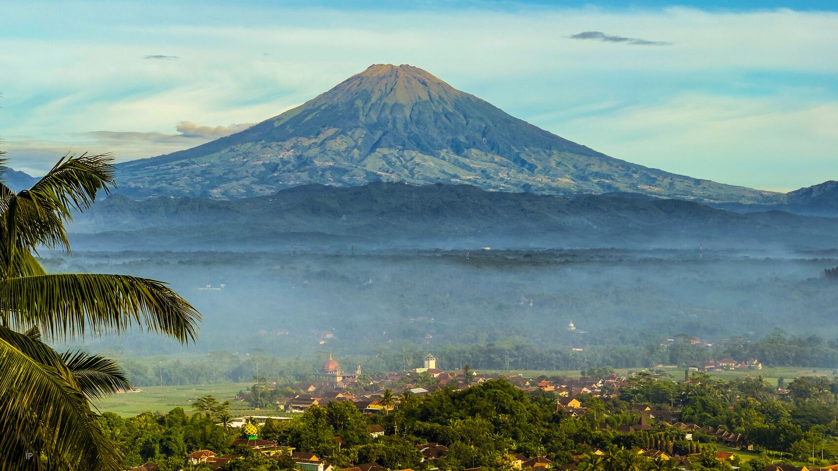 A volcano with a village in the foreground.