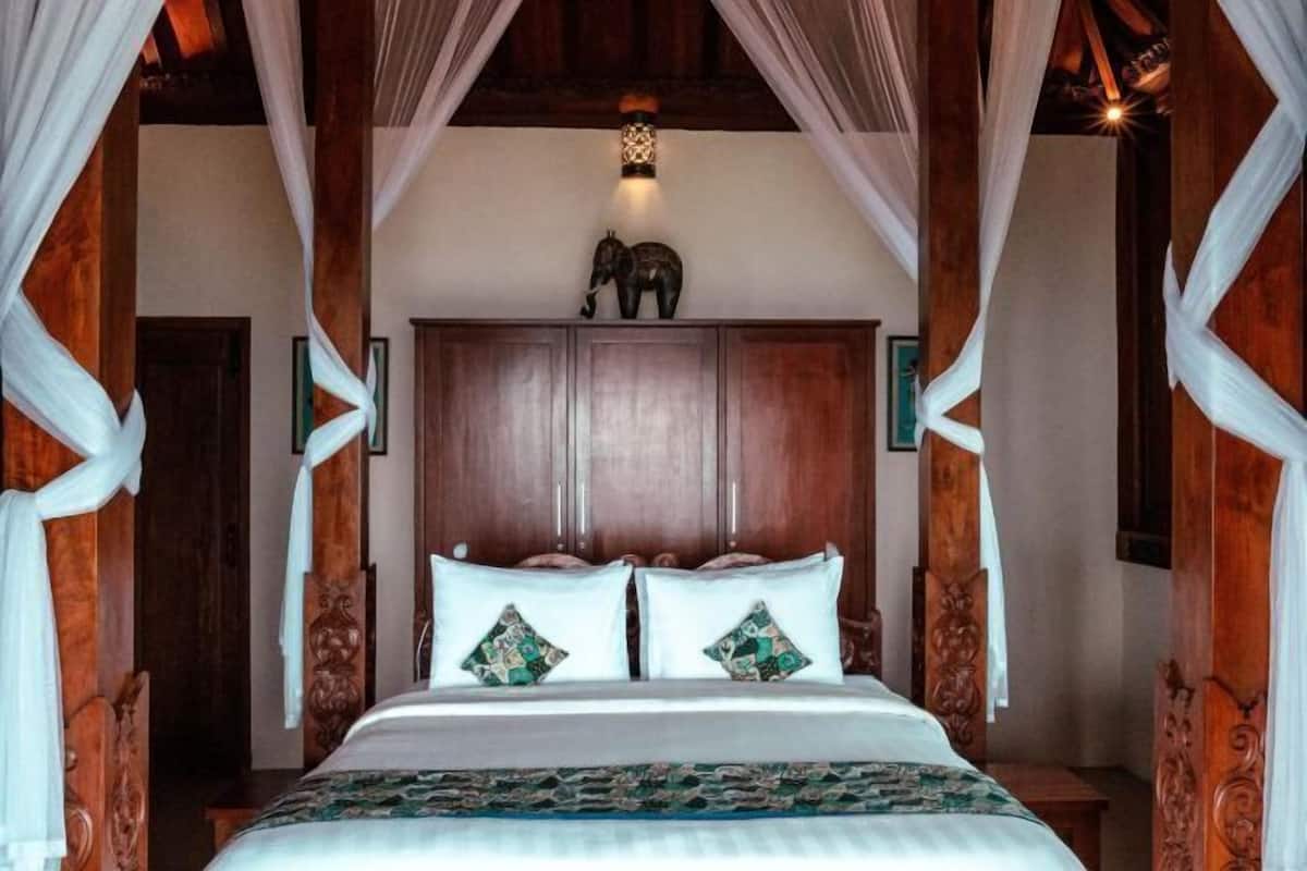 A bed with a canopy, wooden headboard, and decorative pillows.