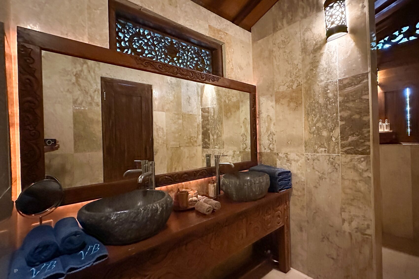 Un baño con un espejo grande, un lavabo de piedra y un mueble de tocador de madera.