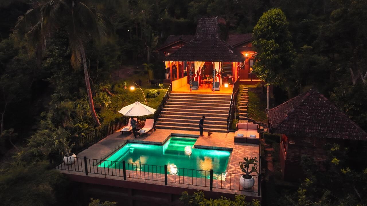 Una villa con piscina, una zona de estar cubierta al aire libre y una escalera que conduce al edificio principal.
