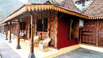 Un bâtiment traditionnel en bois, orné de sculptures complexes, avec un mur rouge et un toit recouvert de tuiles.