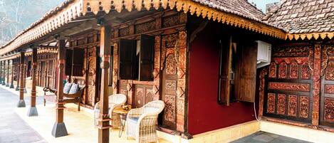 Un bâtiment traditionnel en bois, orné de sculptures complexes, avec un mur rouge et un toit recouvert de tuiles.